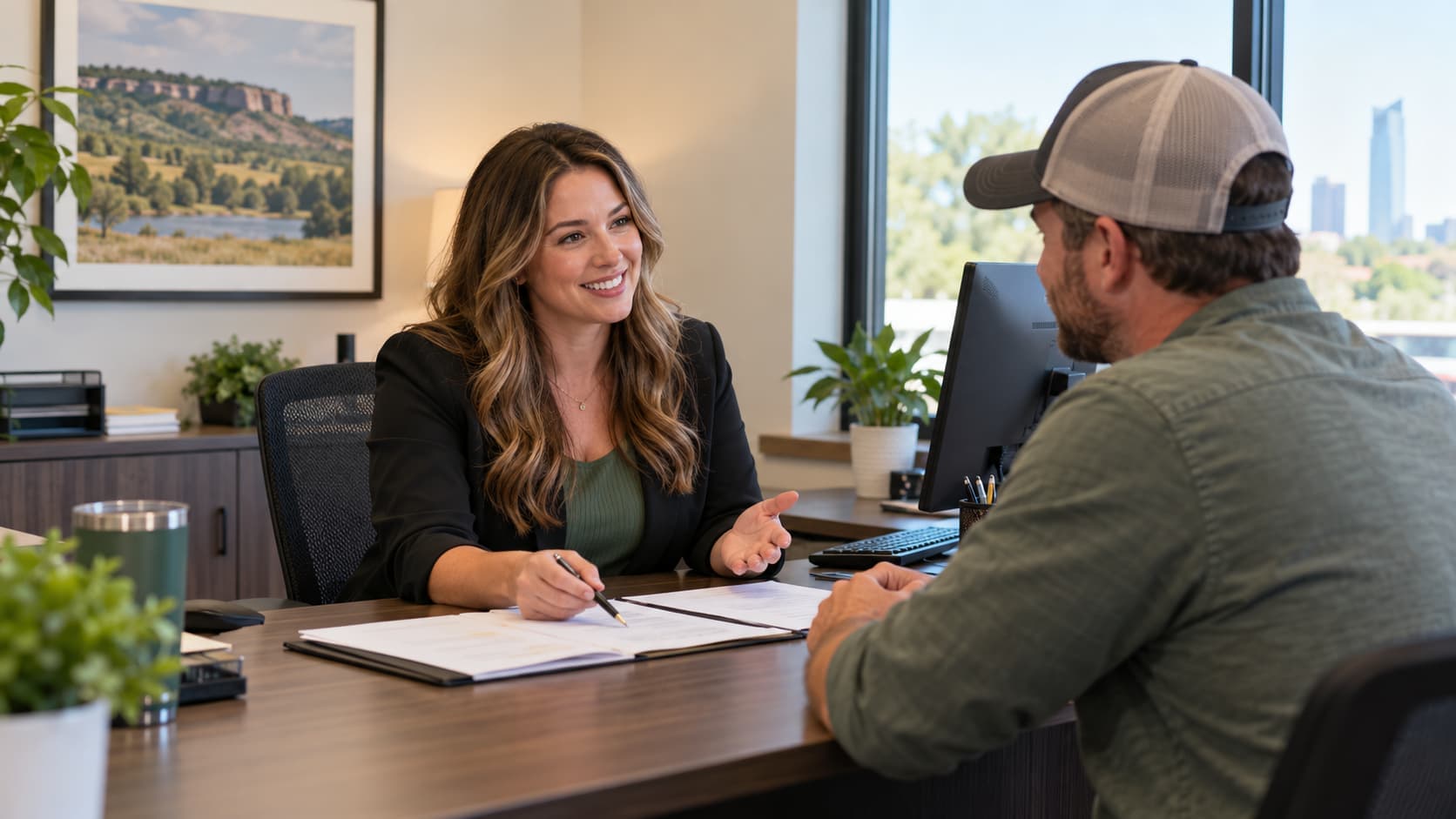Insurance agent discussing coverage options with a customer at an office desk in Tulsa, Oklahoma.