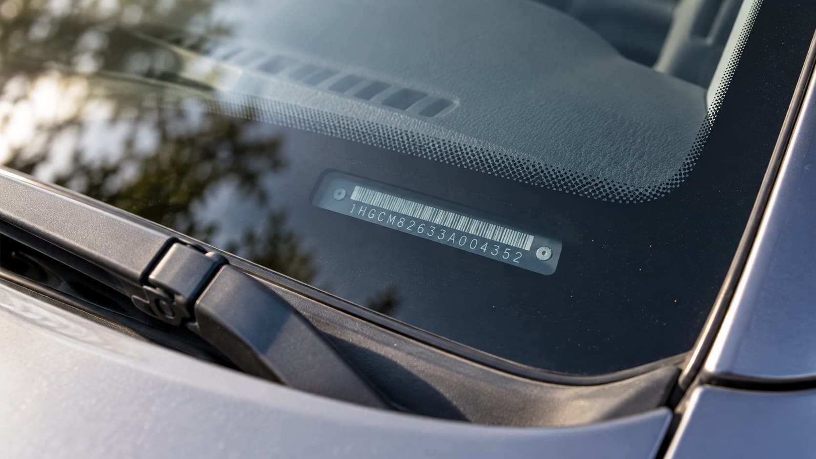Close-up of a vehicle identification number plate at the base of a car windshield